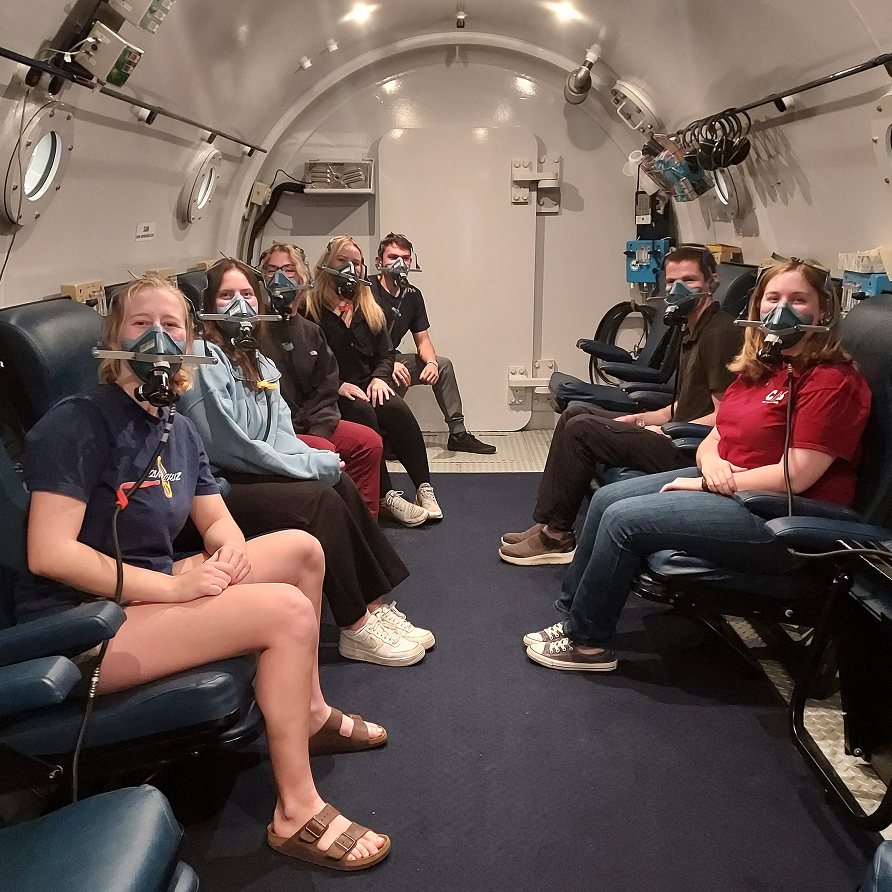 Trainees seated in the chamber wearing oxygen masks